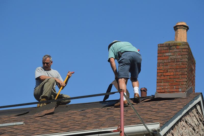 Roofers working next to a brick chimney